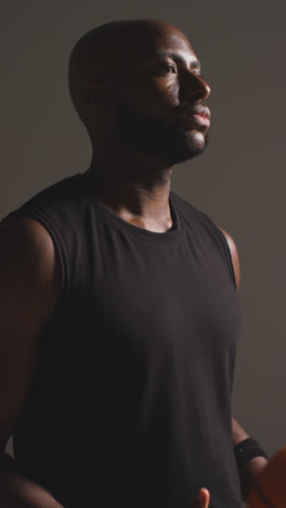 Vertical-Video-Close-Up-Studio-Shot-Of-Male-Basketball-Player-Throwing-Ball-From-One-Hand-To-The-Other